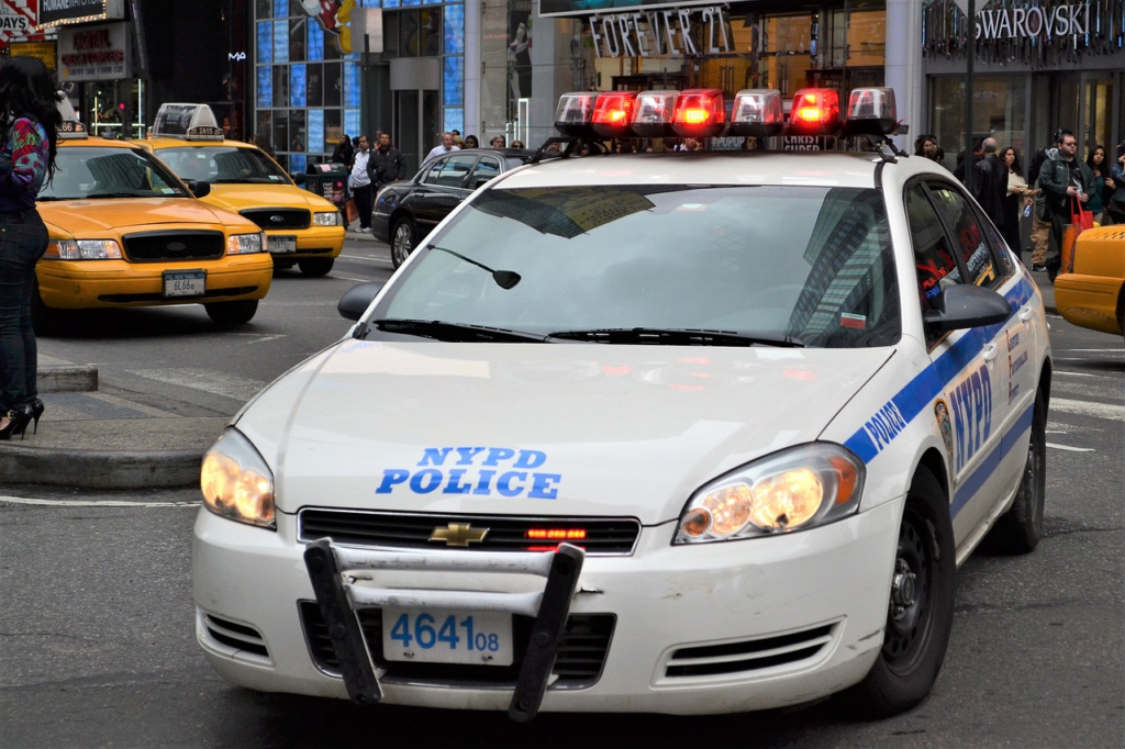 An image featuring a bustling intersection in Florida Village, New York, with police cars, ambulances, and concerned pedestrians